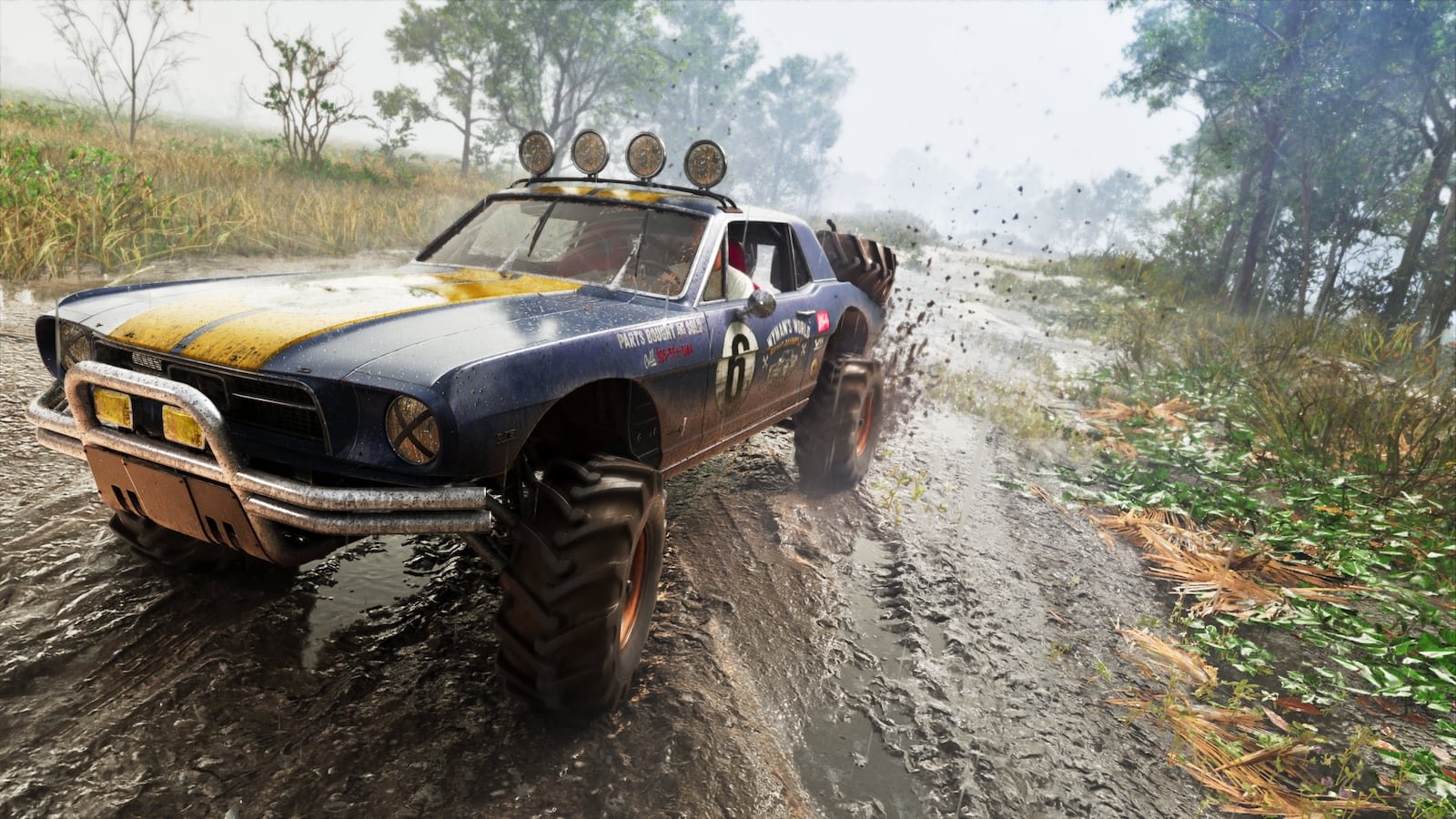 A heavily modified muscle car with oversized off-road tires races through a muddy forest trail kicking up dirt and water.