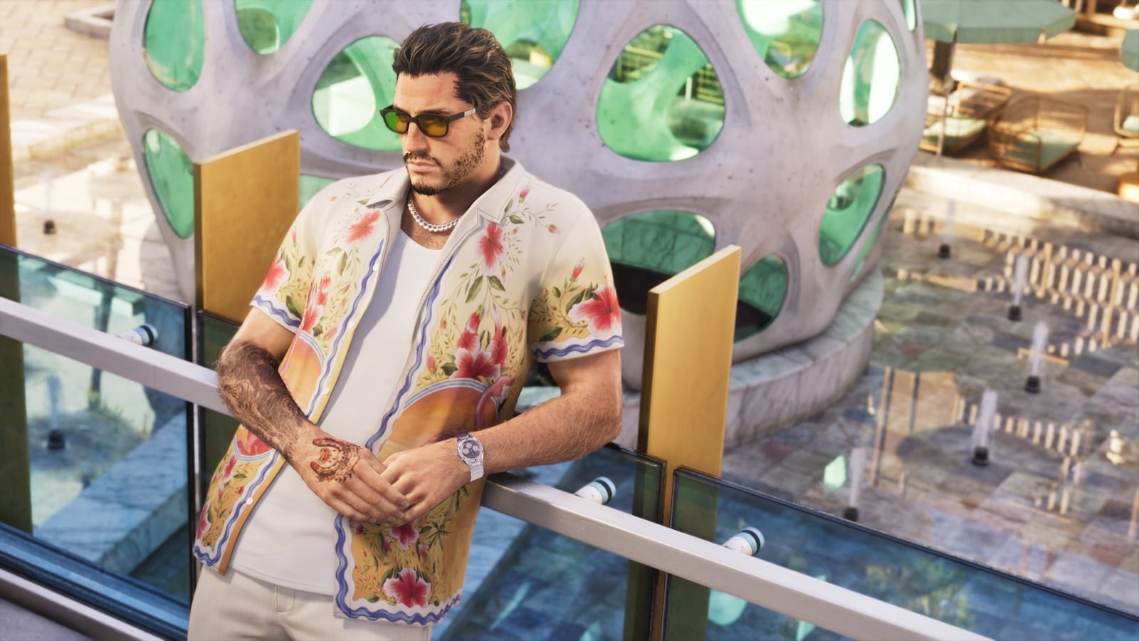 A tattooed man in a floral short-sleeve shirt, sunglasses, and a chain necklace leans on a glass railing near a modern architectural structure.