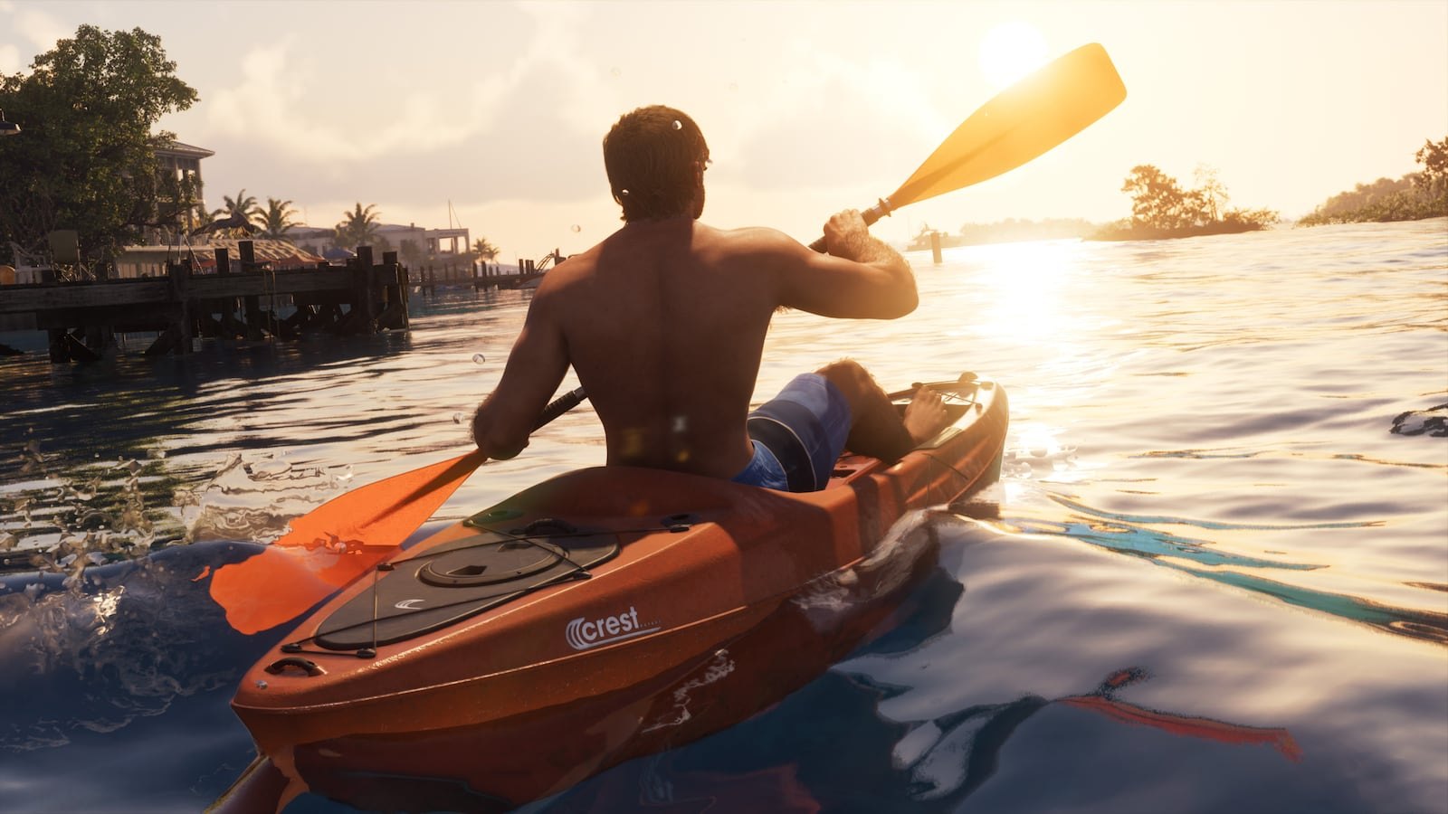 A shirtless man paddles an orange kayak branded 'Crest' across calm water toward a tropical shoreline at sunset.