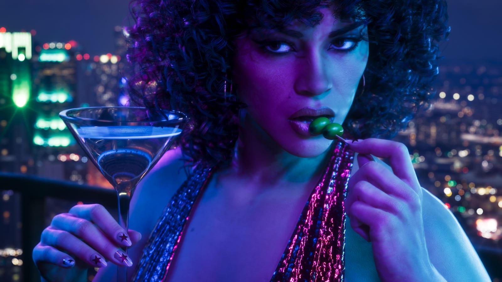 Lucia holding a martini glass and eating an olive on a rooftop at night with a glowing city skyline behind her.