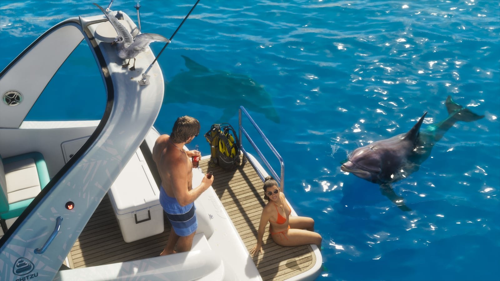 Aerial view of two people on the back deck of a boat surrounded by clear blue water with dolphins swimming alongside.