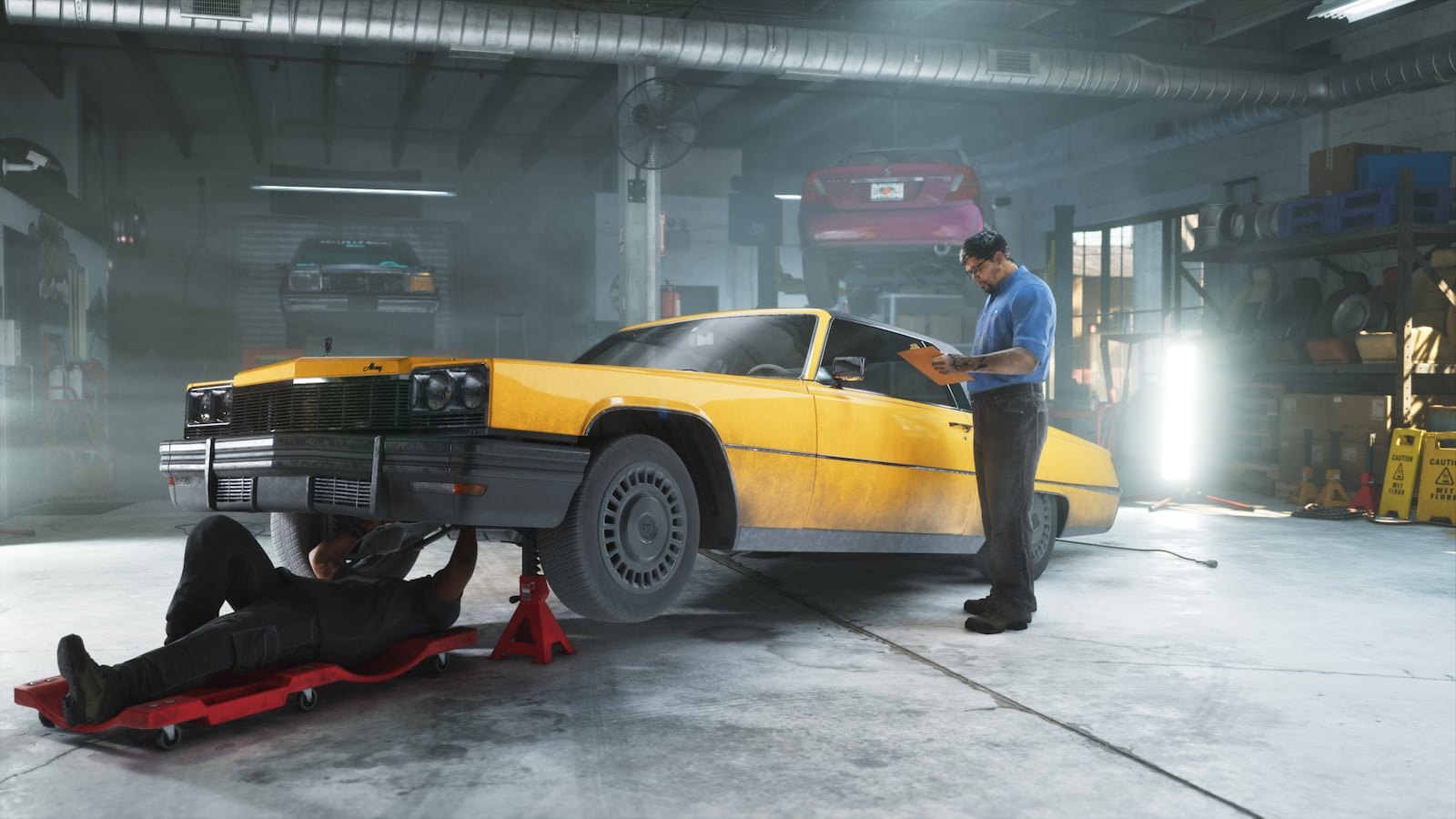 A yellow classic American sedan on jack stands being inspected by two mechanics inside a large automotive workshop.